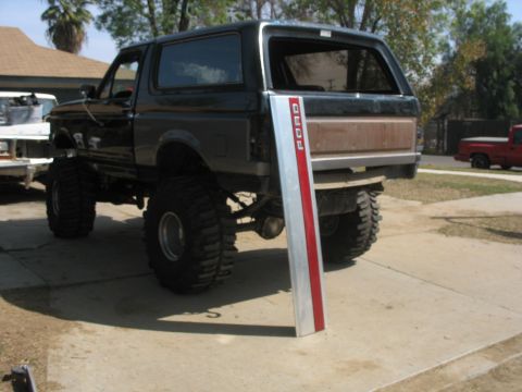 1987 Ford Bronco - This lifted Ford Bronco is parked in a driveway, with a Ford trim piece leaning against its rear.