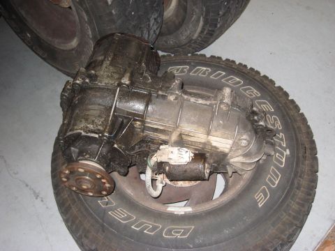 1991 Ford Bronco - A greasy transfer case rests on a Bridgestone tire, with other tires visible in the background.
