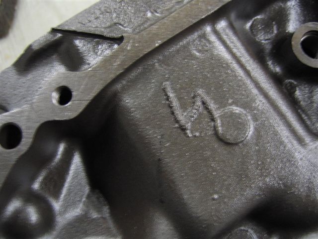 Close-up of a cast metal engine part showing a stamped V6 designation