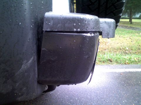 1996 Ford Bronco - Close-up of a vehicle's rear bumper corner and spare tire on a wet day.