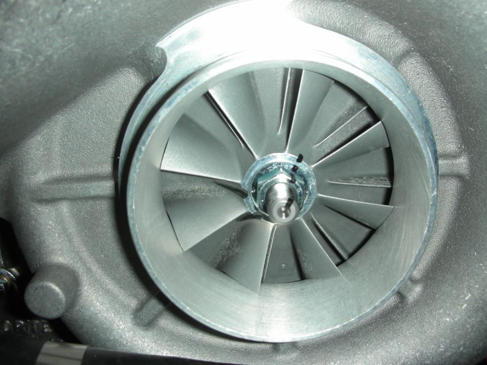 Close-up of a turbocharger compressor wheel with many angled blades