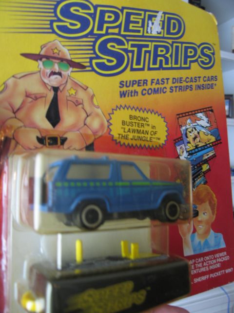 1986 Ford Bronco - A blue diecast SUV with green stripes is shown in its packaging, part of the Speed Strips toy line.