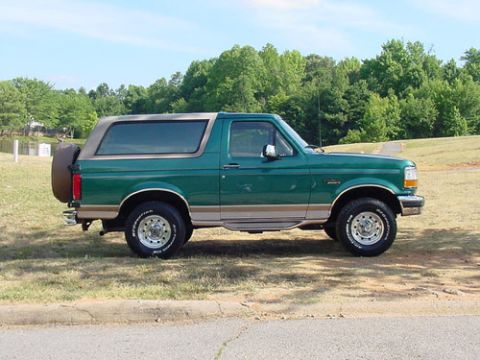1996 Ford Bronco - This green 1996 Ford Bronco is parked on a grassy hill under a clear blue sky.
