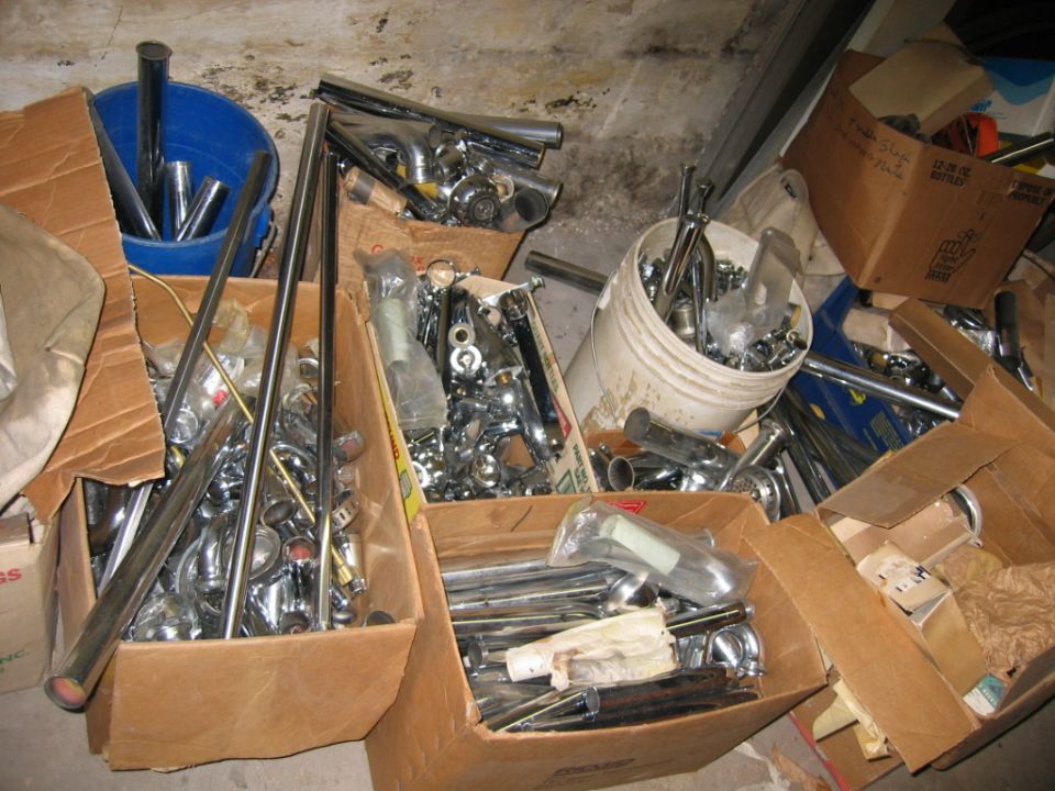 Boxes and buckets filled with chrome trim, exhaust pipes, and other car parts