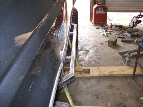 1992 Ford Bronco - Custom rock sliders are being installed on a dark SUV in a workshop setting with welding equipment visible.