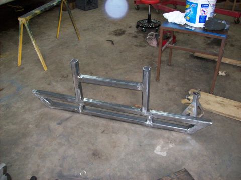 1992 Ford Bronco - A fabricated metal bumper is shown on a workshop floor, ready for installation.