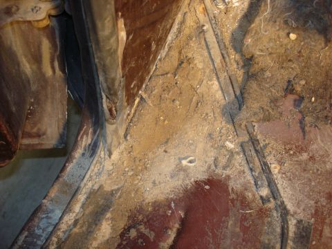 1979 Ford F-250 - Close-up view of a dirty and rusted vehicle undercarriage, revealing structural components and a hose.