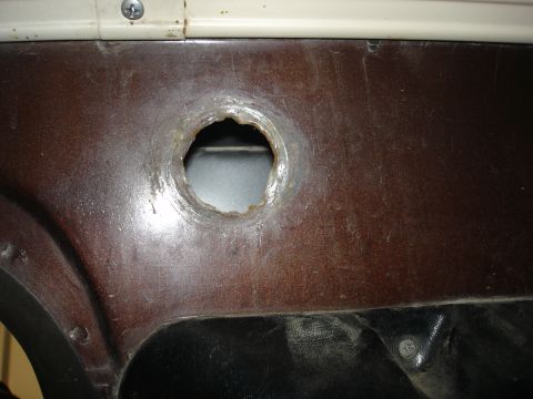 1979 Ford F-250 - Close-up of a vehicle's interior door panel showing a rough circular opening.