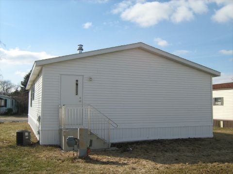 1988 Mercury Grand Marquis - Side view of a white mobile home with an AC unit and stairs leading to the door.