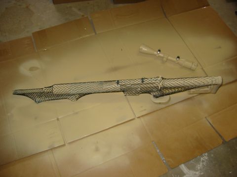 1996 Ford Bronco - Rifle scope being painted with camouflage netting on cardboard.