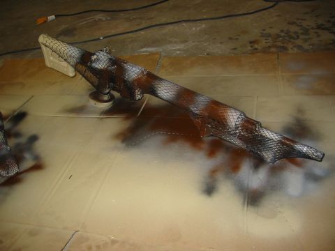 1996 Ford Bronco - A vehicle part is being spray painted with a camouflage pattern using netting for texture.