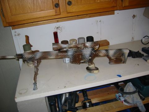 1996 Ford Bronco - A sniper rifle with a custom camouflage paint job sits on a workbench, surrounded by various items.