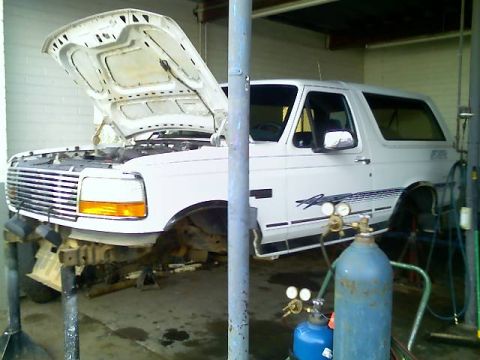 1996 Ford Bronco - White 1996 Ford Bronco undergoing maintenance with welding equipment present.