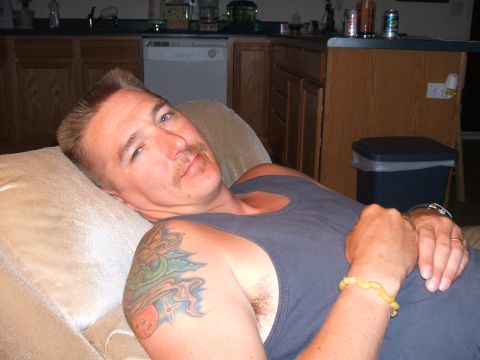 1974 Ford Ranchero - A man with a mustache and a colorful tattoo on his shoulder is seen relaxing on a couch.