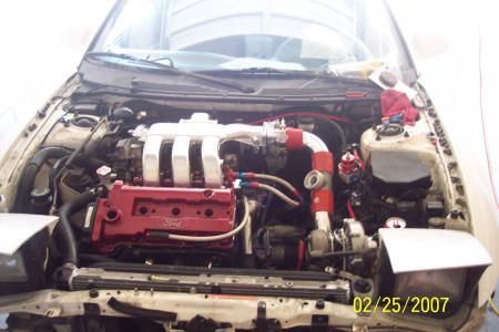 1994 Ford Probe - The engine bay of a car is shown with custom modifications and a red Ford valve cover.