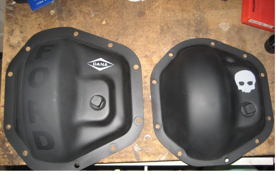 Two black differential covers, one with DANA logo, the other with a white skull sticker