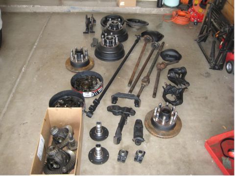 1996 Ford Bronco - Various vehicle axle and brake parts are spread across the floor, including differential assemblies and brake drums.