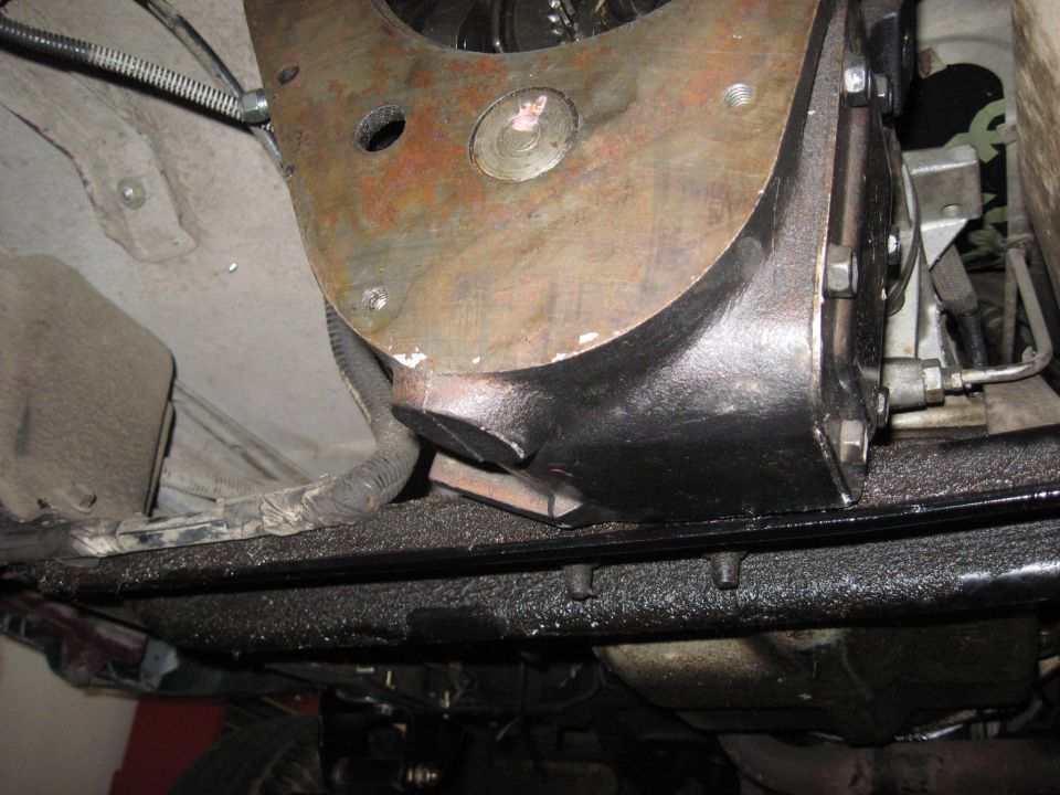 Undercarriage view of a vehicle's transmission housing and frame, showing oil residue and wiring