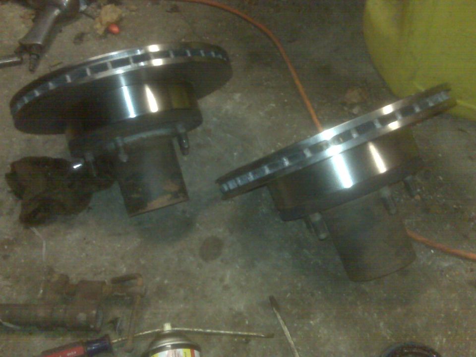 Two brake rotors on a concrete floor.
