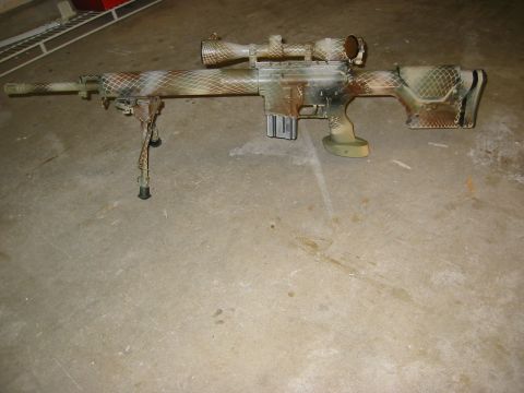 1996 Ford Bronco - A camouflage-painted sniper rifle with a scope and bipod rests on a concrete floor.