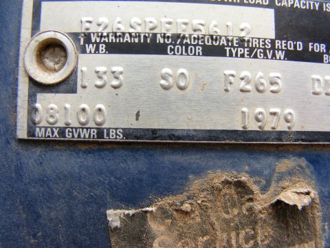 1985 Ford Bronco - A close-up view of a vehicle's identification plate, showing embossed text and numbers, including a VIN and manufacturing date.