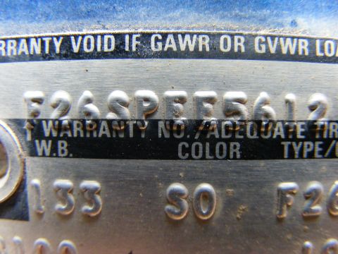 1985 Ford Bronco - A close-up shot of a metal VIN plate on a vehicle, showing embossed text and numbers. The plate includes text such as "WARRANTY VOID IF GAW…