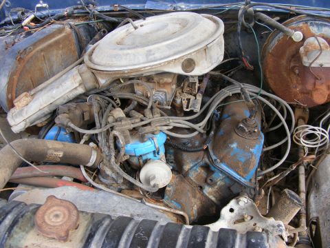 1985 Ford Bronco - A close-up view of a heavily weathered and dirty engine bay, likely from an older Ford vehicle. The engine components, including the air cl…