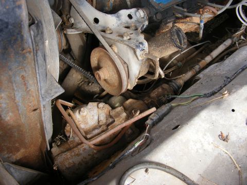 1985 Ford Bronco - A close-up view of the engine bay of a vintage Ford Bronco, showing the fan, belts, pulleys, and various hoses and wiring.