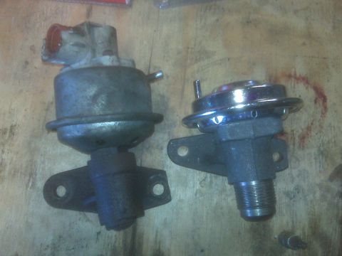 1995 Ford Bronco - Two automotive wastegate actuators are shown on a wooden surface. The actuator on the left is silver and grey with a red opening, while the…