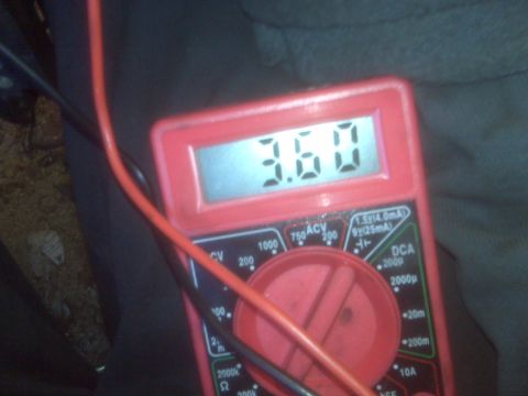 1995 Ford Bronco - A red digital multimeter displays a reading of 3.60 volts. The multimeter has red and black probes connected, with the red probe prominentl…
