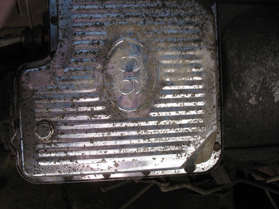 Dirty chrome transmission pan with '302' emblem.