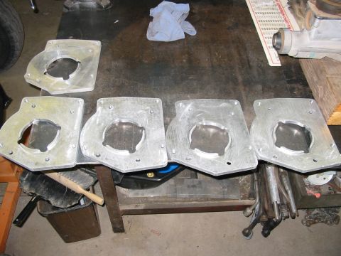 1993 Ford Taurus - Four aluminum adapter plates with circular cutouts are laid out on a workbench. A blue shop rag and a paper document are visible in the bac…