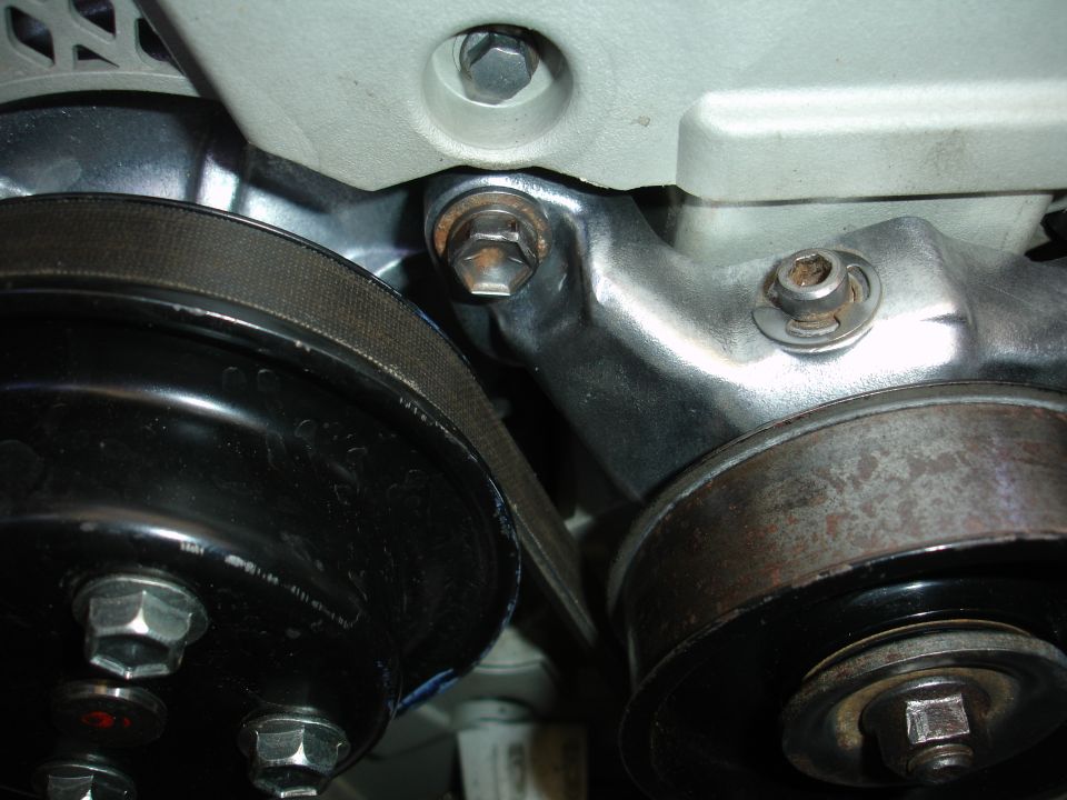 Close-up of engine crankshaft pulley, V-belt and idler pulley on a silver timing cover