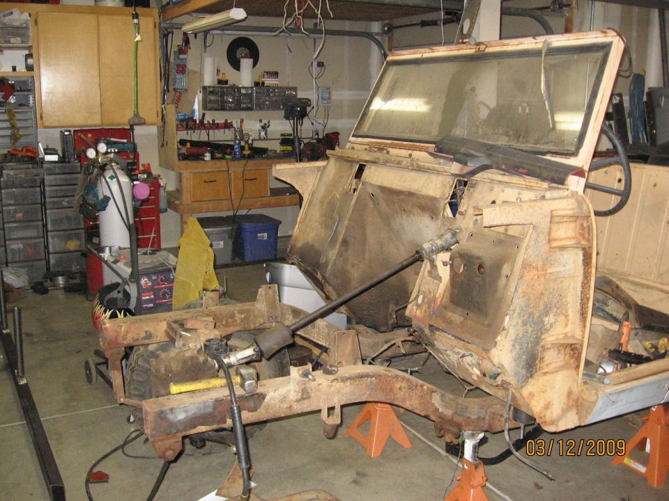 Scout project with engine and front sheetmetal removed, bare frame rails on jack stands