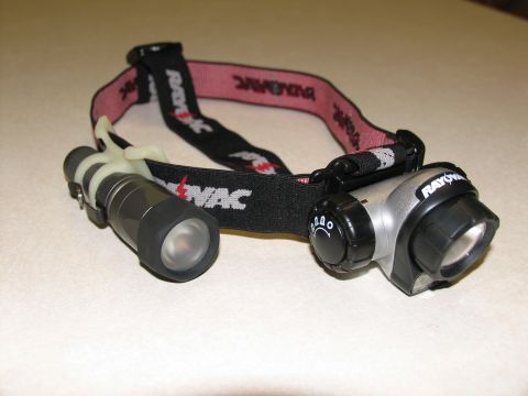 1984 Ford Bronco - A black and pink Rayovac brand headlamp with two lights is shown resting on a speckled white surface.
