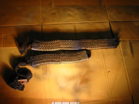 1996 Ford Bronco - Two black mesh tubes are laid out on a brown cardboard surface. One tube is slightly longer and straighter than the other, which is curled…