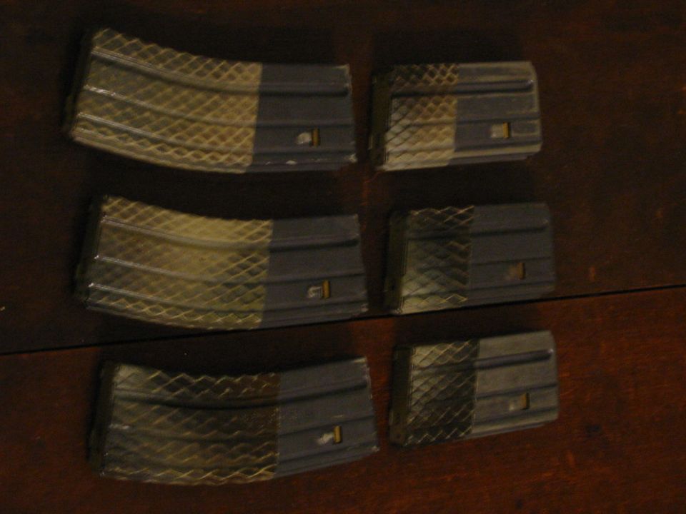 Six rifle magazines on a wooden surface