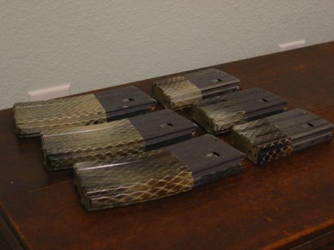 1996 Ford Bronco - Seven rifle magazines are arranged in a hexagonal pattern on a wooden surface. The magazines have a dark gray metal base and a patterned wr…