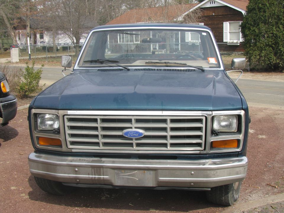 Dark teal Ford pickup truck front view with chrome bumper and grille