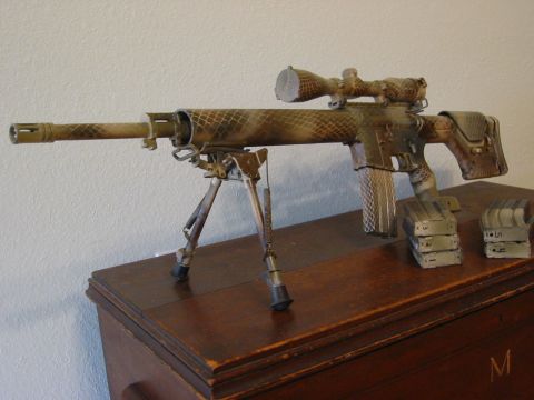 1996 Ford Bronco - A camouflage-painted sniper rifle with a scope and bipod rests on a wooden surface. Two stacks of magazines are placed to the right of the…