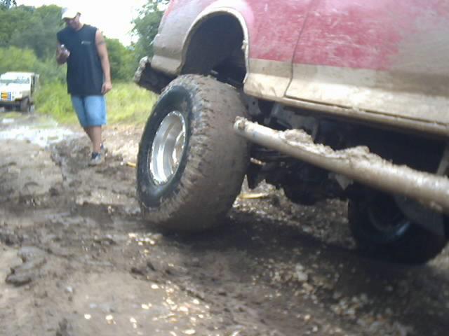 Muddy red SUV with a person standing nearby and another vehicle in the background