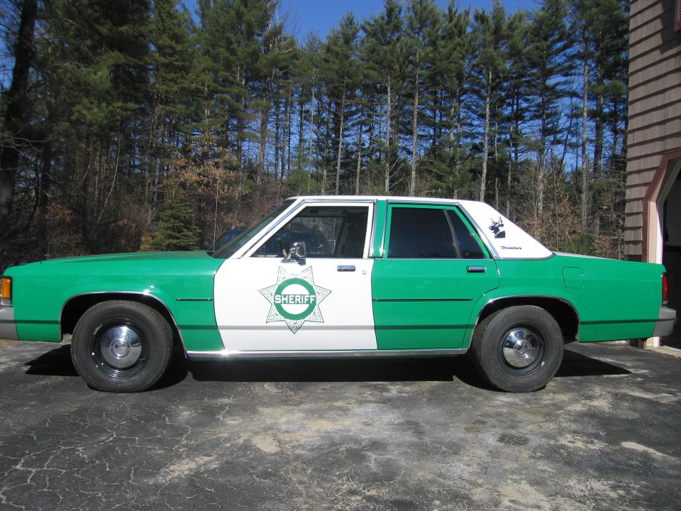 Driver-side profile of a green and white Ford Sheriff car with star badge