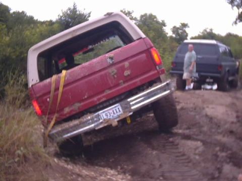 1989 Ford Bronco - Off-roading adventure: a 1989 Ford Bronco gets stuck in the mud, with a second vehicle waiting behind.