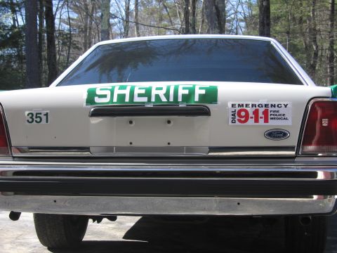 1991 Ford LTD Crown Victoria - Rear view of a white-and-green SHERIFF sedan showing the trunk placard, 351 decal, DIAL 911 sticker and Ford emblem.