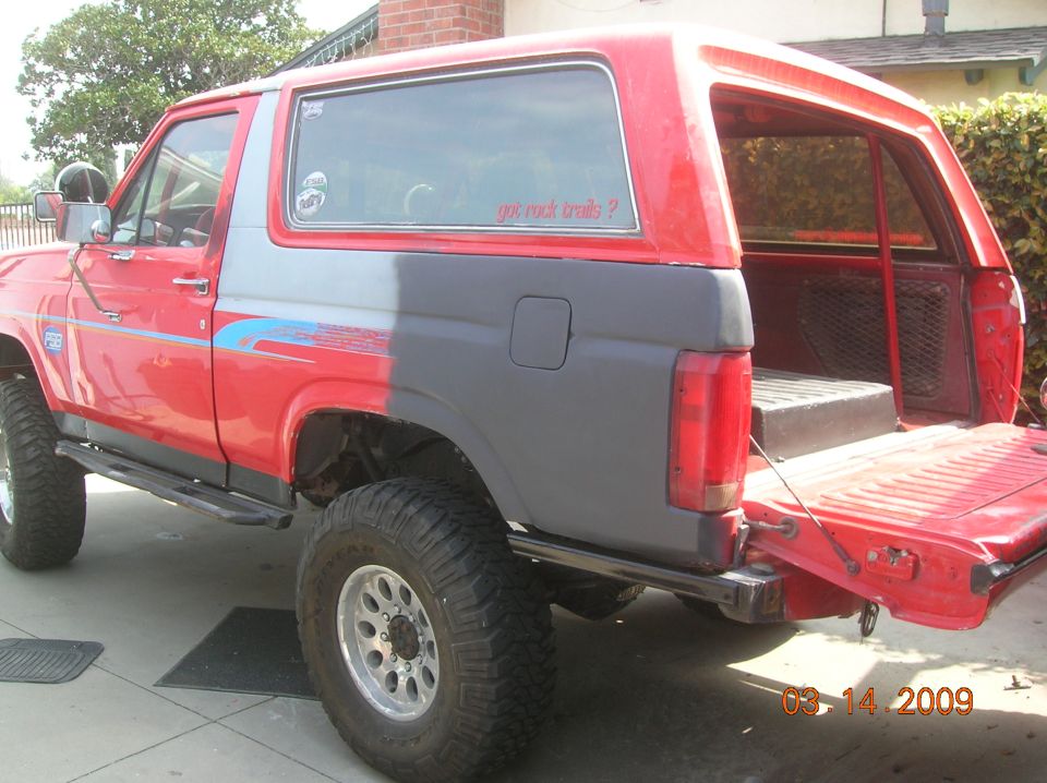 1985 Ford Bronco RED WAGON rear passenger side view, red and gray paint, off-road tires, tailgate down