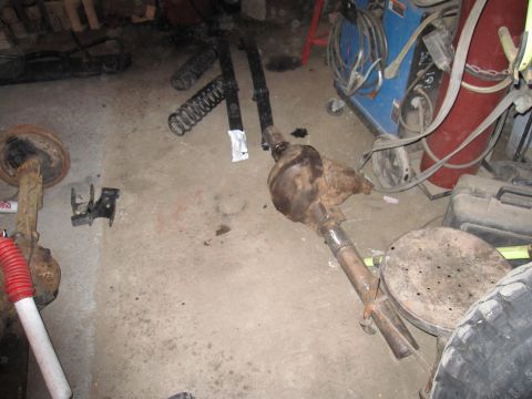 1992 Ford Bronco - Photograph of axle housings and suspension components on a garage floor, not a document.