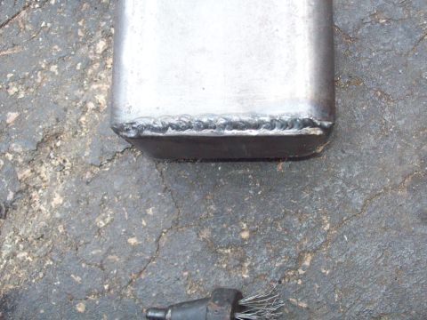 1989 Ford F-150 - A close-up view shows a welded metal joint on what appears to be the bottom of a vehicle part, possibly an exhaust pipe, resting on a crack…