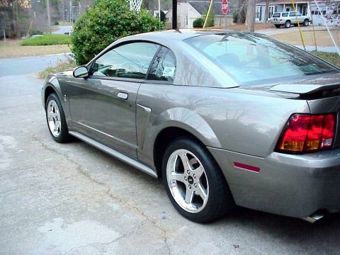 2001 Ford Mustang - A gray 2001 Ford Mustang coupe is shown from the rear three-quarter angle on a residential driveway.