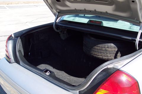 2001 Ford Crown Victoria - The open trunk of a silver 2001 Ford Crown Victoria reveals a spare tire and the car's interior. The trunk is clean and appears to be in go…