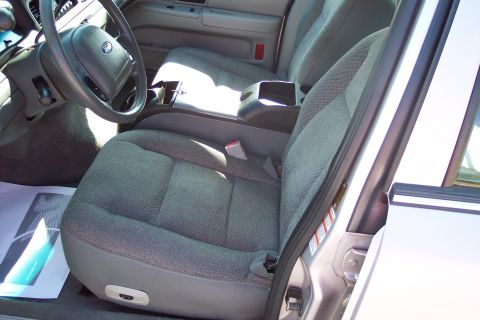 2001 Ford Crown Victoria - Interior view of the driver's side front seat and center console of a Ford Crown Victoria. The gray fabric seats and dashboard are visible.